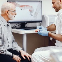 A dentist explaining how a denture works to a patient.