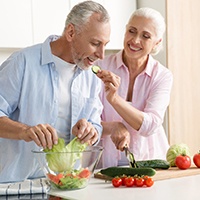 An older couple preparing a salad together.
