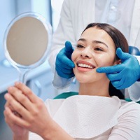Woman smiling at reflection in handheld mirror