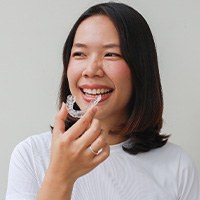 Smiling patient holding clear aligner
