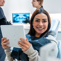 Patient smiling while holding mirror in treatment chair