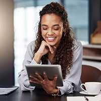 Woman with beautiful smile looking at tablet at work