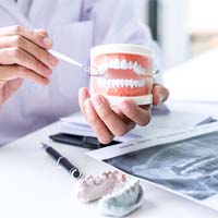 Denture dentist in Covington holding a model of teeth