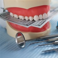 An artificial jaw mockup with money and dental instrument on table
