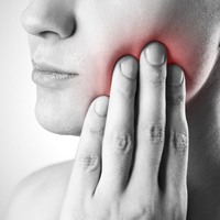 A woman with tooth pain in need of emergency dentistry