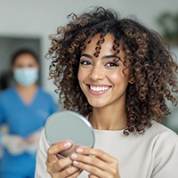 Woman smiling while holding small mirror