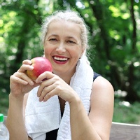 Woman with dental implants in Covington, GA about to eat an apple
