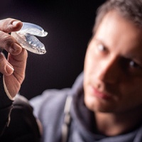 Male athlete with dental implants in Covington, GA holding a mouthguard