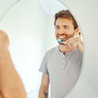 Man in front of mirror, holding toothbrush