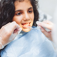 Dentist putting clear aligner on teenage girl