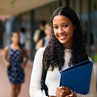 Teenage girl smiling while holding blue binder