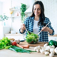 Woman smiling while making salad in white kitchen