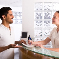 Happy patient talking with dental receptionist about payment options