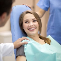 Young woman smiling with a dentist and team member.