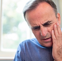 Man in need of emergency dentistry holding jaw