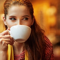 A woman sipping coffee out of a mug.