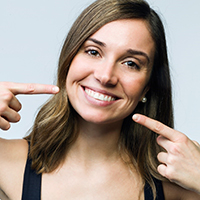 Woman smiling and pointing to veneers in Covington