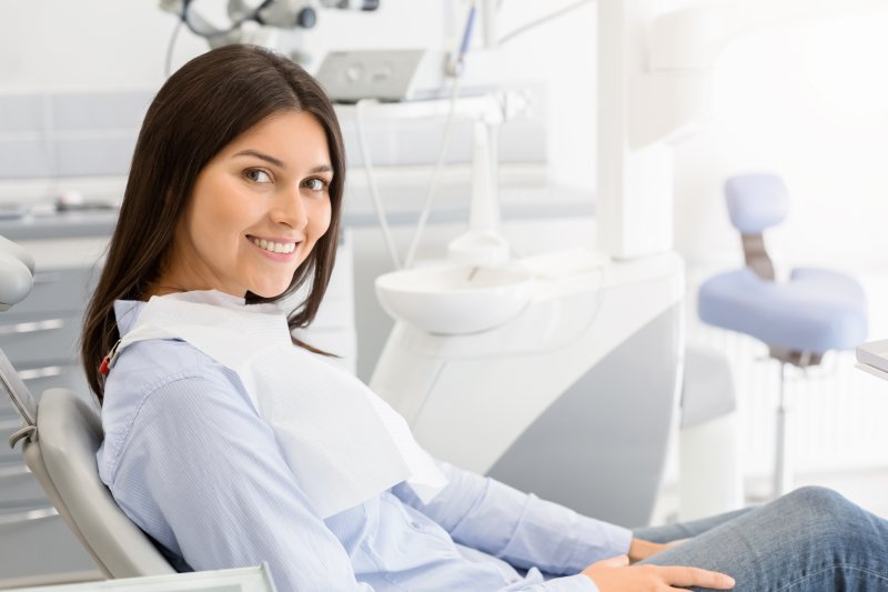 a young woman seated in a dentist’s chair preparing for a dental procedure that requires an anesthetic