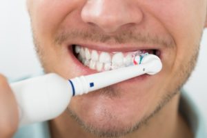 man using electric toothbrush 