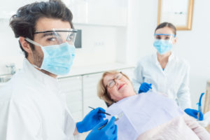 Two dentists wearing personal protection equipment with patient