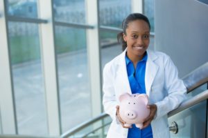 dentist holding pink piggy bank 