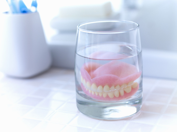 full denture soaking in glass of water