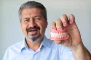 Man holding his dentures after cleaning them.