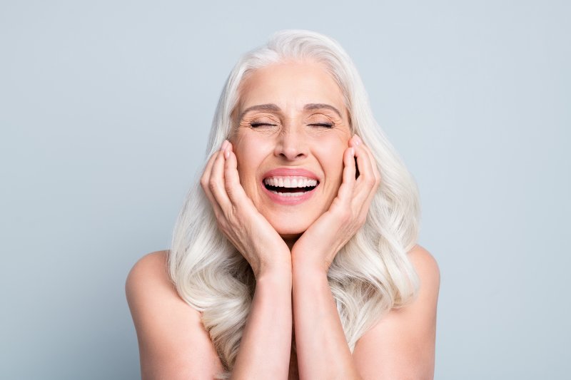 An older woman smiling with her dental implants