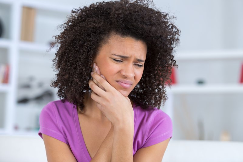 Woman holding her jaw due to a dental emergency