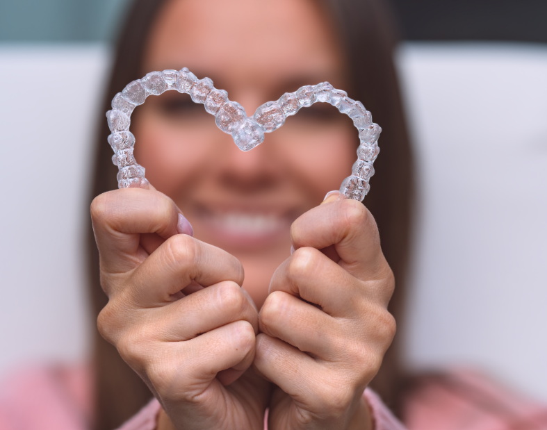 Woman holding clear aligners in heart shape