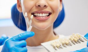Dentist holding up veneers to smiling patient in dentist’s chair.